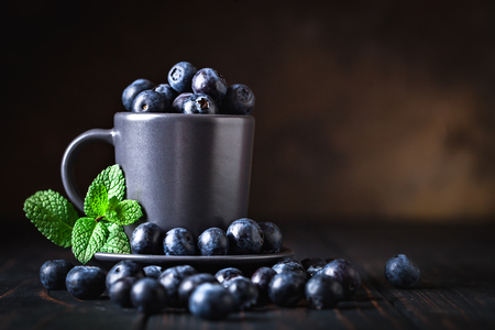Raspberries and blueberries in a Cup on a darkの写真素材