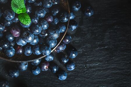 Juicy and fresh blueberries with green leaves on rustic table. Blueberry antioxidant. Concept for healthy eating and nutrition. Selective focus.の写真素材