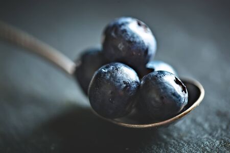 Juicy and fresh blueberries with green leaves on rustic table. Blueberry antioxidant. Concept for healthy eating and nutrition. Selective focus.の写真素材