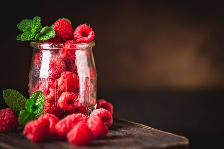 Raspberries in a Cup on a dark background. Summer and healthy food concept. Background with copy space. Selective focus. Vertical.の写真素材