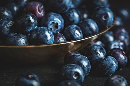 Juicy and fresh blueberries with green leaves on rustic table. Blueberry antioxidant. Concept for healthy eating and nutrition. Selective focus.の写真素材