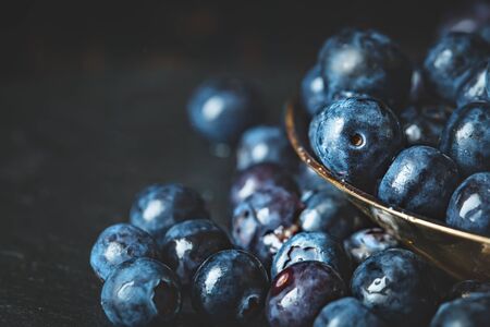 Juicy and fresh blueberries with green leaves on rustic table. Blueberry antioxidant. Concept for healthy eating and nutrition. Horizontal.の写真素材