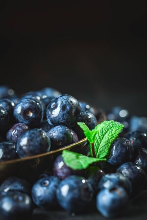 Juicy and fresh blueberries with green leaves on rustic table. Blueberry antioxidant. Concept for healthy eating and nutrition. Selective focus.の写真素材