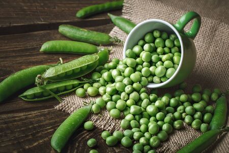 Delicious ripe green peas lying on a wooden table.の写真素材