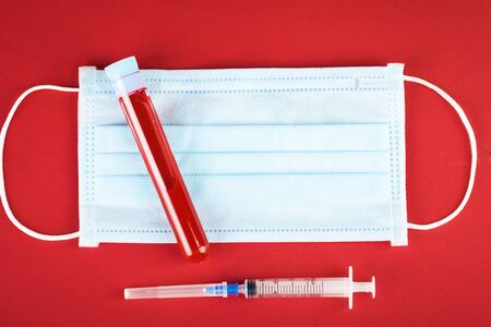 Medical mask and a test tube with a blood test on table. Coronavirus Pandemic. Horizontal.の写真素材