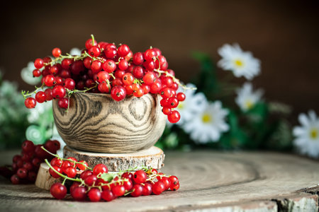 Fresh red currants in plate on dark rustic wooden table. Background with copy space. Selective...