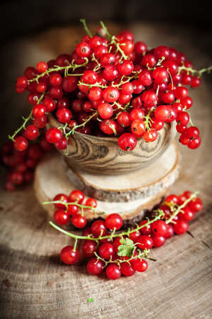 Fresh red currants in plate on dark rustic wooden table. Background with copy space. Selective focus. Vertical.の写真素材