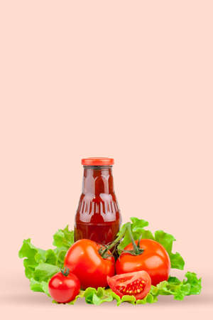 Tomatoes, tomato ketchup and tomato juice with lettuce leaves, isolated on a pink background. Vertical.の写真素材