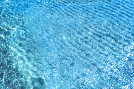 Background shot of aqua water surface. Swimming pool with sunny reflections.