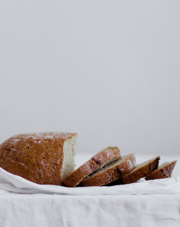 4 slices and a half of fresh baked bread with a golden brown crust lies on a white towel side view...