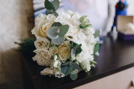 Close-up of elegant white flower bouquet with roses and eucalyptus, symbolizing romance, happiness, and the start of a new married life.の写真素材