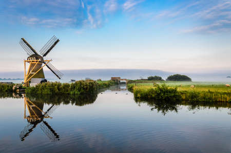 Windmill in a beautiful landscape durring a misty morningの写真素材