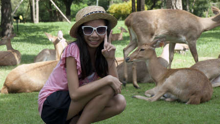 A girl posting cute next to a deers in a zooの写真素材