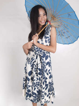 A cute young woman holding blue silk umbrellaの写真素材