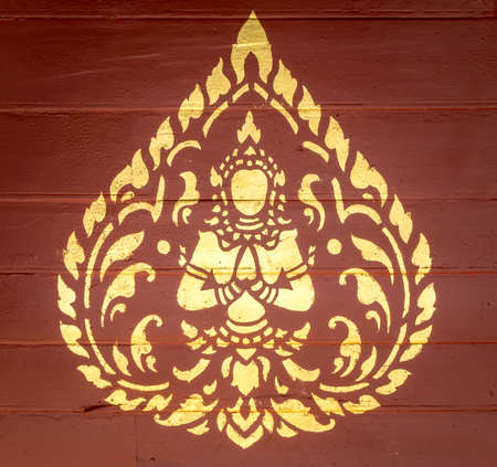 Golden Thai-Style Angel Art on the Red Wooden Wallの写真素材
