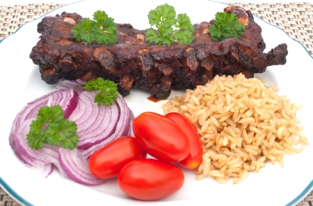 Grilled  spare ribs in  barbecue sauce with rice, tomato, onions and parsleyの写真素材
