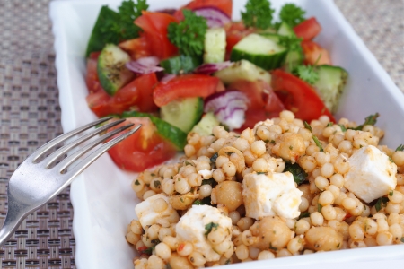 Couscous feta cheese and chickpeas salad with tomatoes, cucumbers and onionsの写真素材