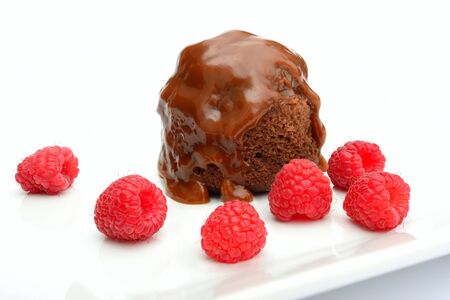 Chocolate caramel pudding with raspberries on white plateの写真素材