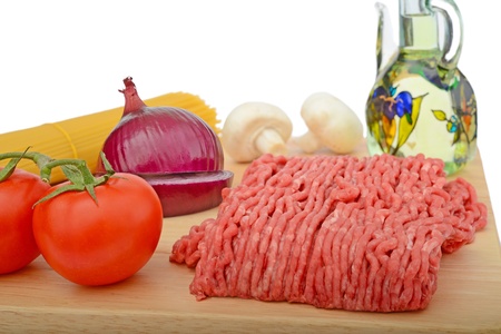 spaghetti bolognese preparation  ingredients on cutting board, tomatoes, onion, pasta, oil, mince beefの写真素材