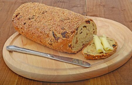 fruit and seeds loaf with knife and butter on cutting boardの写真素材