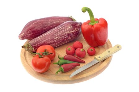 Aubergines, tomatoes, sweet pepper and radish on cutting board isolated on whiteの写真素材