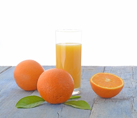 Oranges and glass of orange juice on wooden tableの写真素材