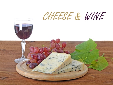 blue cheese on cutting board with a glass of red wine and vine leavesの写真素材