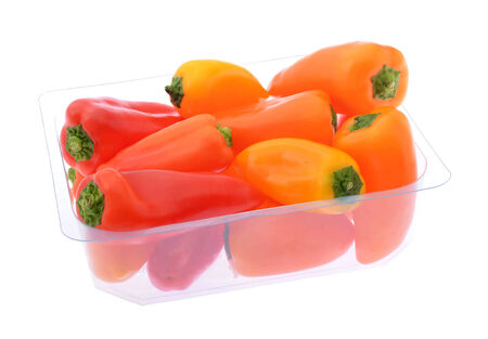 Small sweet yellow, orange and red peppers in plastic container isolated on whiteの写真素材