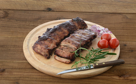 Roasted ribs, tomatoes, onions and herb on wooden chopping boardの写真素材
