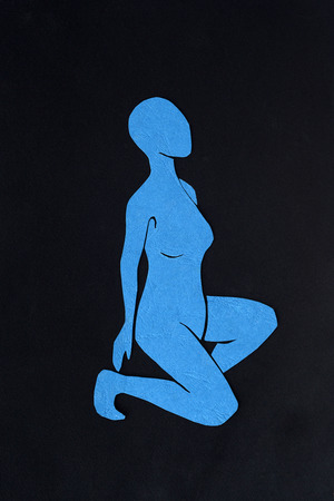 Cut-out blue paper female figure on black backgroundの写真素材