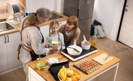 Multi-generational family members explore new and tasteful recipes on a tablet, make healthy food choices, cook, and enjoy meals together. Family gatherings help renew and strengthen relationships.の写真素材