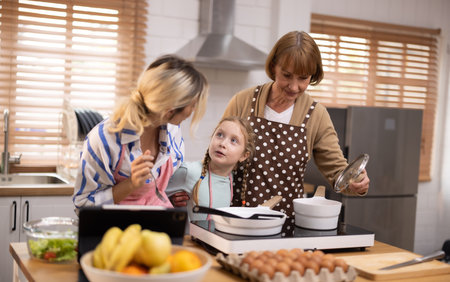 Multi-generational family members explore new and tasteful recipes on a tablet, make healthy food choices, cook, and enjoy meals together. Family gatherings help renew and strengthen relationships.の写真素材