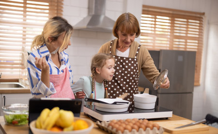 Multi-generational family members explore new and tasteful recipes on a tablet, make healthy food choices, cook, and enjoy meals together. Family gatherings help renew and strengthen relationships.の写真素材