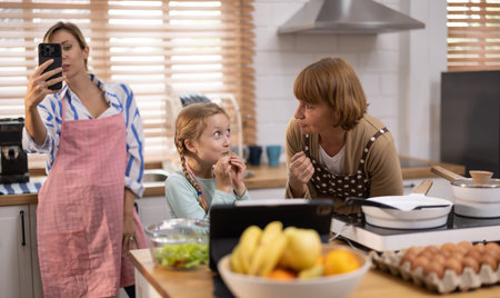 Multi-generational family members explore new and tasteful recipes on a tablet, make healthy food choices, cook, and enjoy meals together. Family gatherings help renew and strengthen relationships.の写真素材