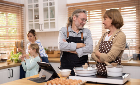 Multi-generational family members explore new and tasteful recipes on a tablet, make healthy food choices, cook, and enjoy meals together. Family gatherings help renew and strengthen relationships.の写真素材