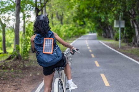 Female cyclist combine eco-consciousness with active lifestyle, using bikes for workout and travel, a portable solar panel for device charging, and embracing recycling practices for circular economy.の写真素材