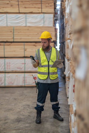 Logistics workers in wooded pallets warehouse using technological tools to manage flow of goods, including software, barcode scanners, notes to accurately label, verify products in factory storehouseの写真素材