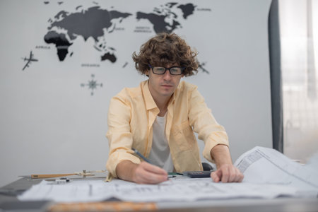 Multicultural team of architects collaborates on a low-carbon building project, analyzing blueprints, drafting layouts, calculating precise structures and materials for eco-friendly construction.の写真素材