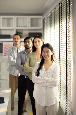 A portrait of a multicultural startup team standing in line, showcasing confidence and unity in their contemporary office space, emphasizing collaboration and diversity.の写真素材
