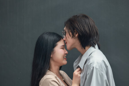 Asian lovers engage in playful interactions outdoors. Their eyes meet with affectionate gaze, radiating love and tenderness. Laughing and sharing intimate moments filled with warmth and playfulness.の写真素材