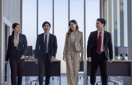A team of four business professionals walking confidently together in a modern office environment, symbolizing teamwork and collaboration.の写真素材