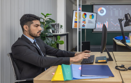 Professional businessperson in a suit is deeply focused on laptop in a modern office. Concentration and seriousness for corporate work environments and business decision-making scenarios.の写真素材