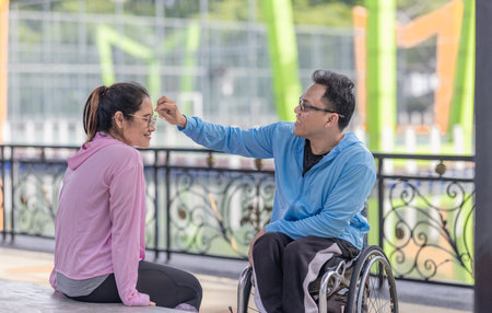 A couple takes turns wiping each other's sweat during an outdoor activity, sharing a caring and supportive interaction that highlights their bond and mutual affection.の写真素材