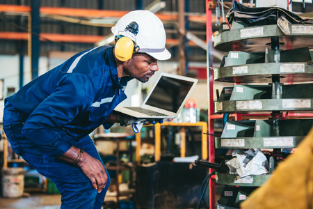 Industrial technician monitoring factory's inventory operation, analyzing smoothness, efficiency. Updating integrated database for optimum productivity. Focusing on cost-effectiveness and safetyの写真素材