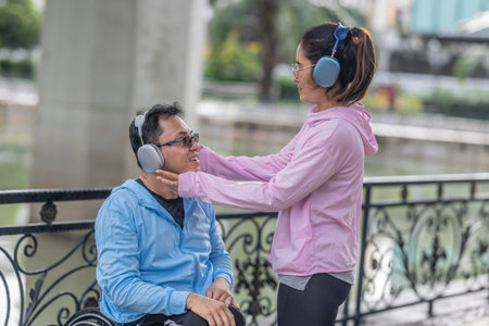 A couple enjoys an outdoor moment, listening to music with headphones while selecting a playlist on their smartphone, highlighting relaxation, technology, and togetherness.の写真素材