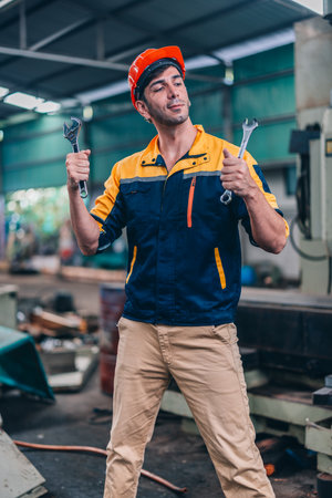 A worker stands in an industrial workshop, showcasing confidence with arms crossed and tools held firmly in both hands.の写真素材