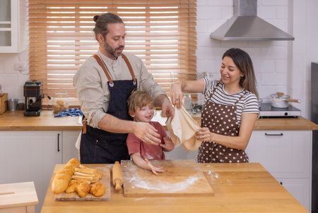 A family is happily engaged in baking at home, with a child playfully participating as they prepare...