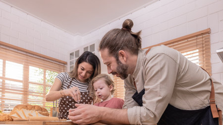 A family is happily engaged in baking at home, with a child playfully participating as they prepare...