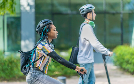 Young people commuting to work using eco-friendly transportation including electric scooters and folding bicycles, encouraging environmentally conscious and sustainable transportation.の写真素材