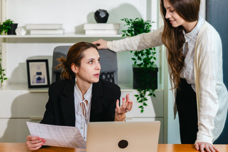 The professional business team engaged in a discussion with a laptop in a modern office setting, as...